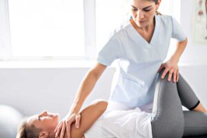 A chiropractor explains a spine model to a patient in a well-lit clinic room.